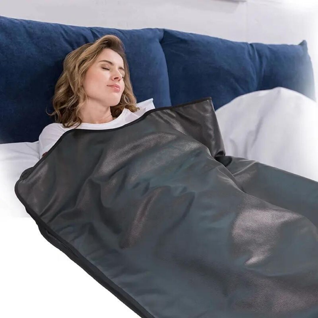 A woman on a bed enjoying a home sauna with the RegenHeat infrared sauna blanket