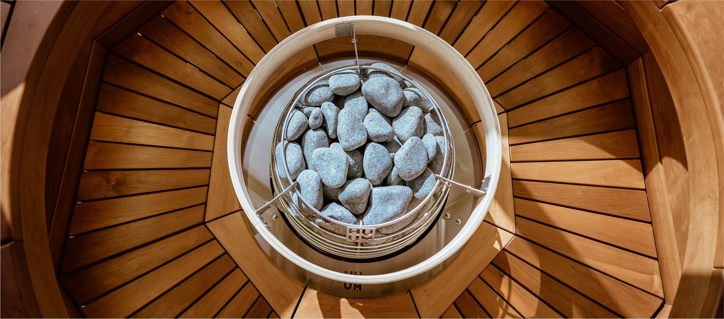 Home sauna recovery with circular bowl of rocks on wooden floor.
