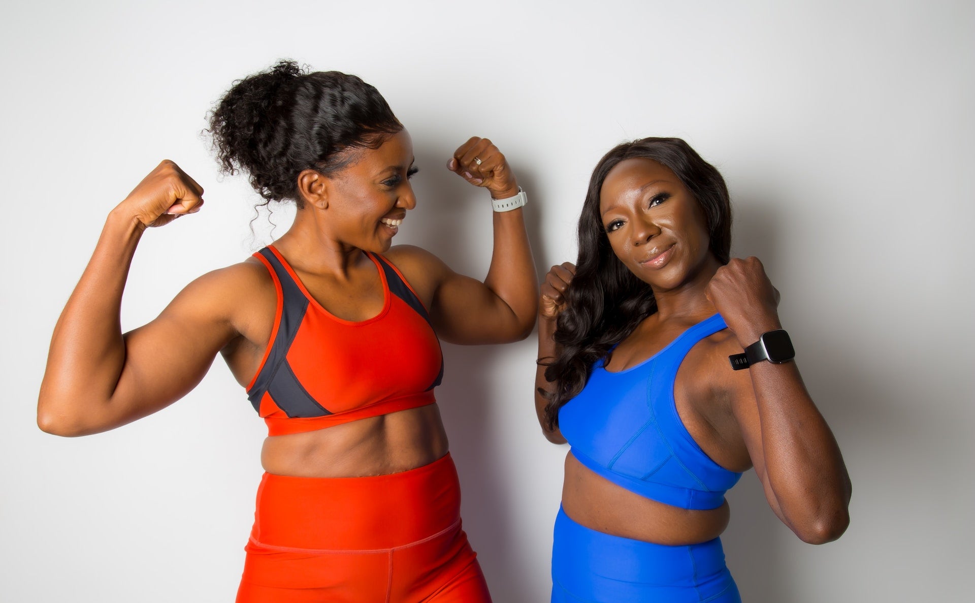 Two women in sports attire flexing their muscles.